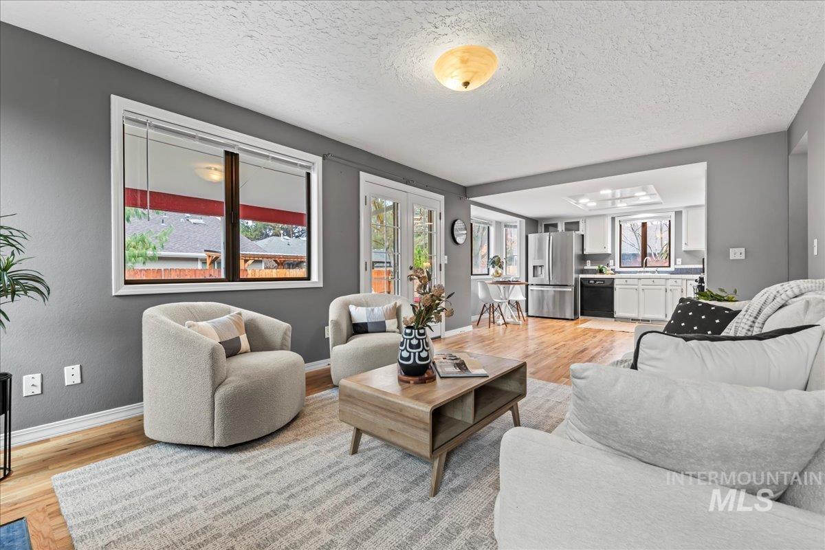 Living room with light wood-style flooring, a textured ceiling, and french doors