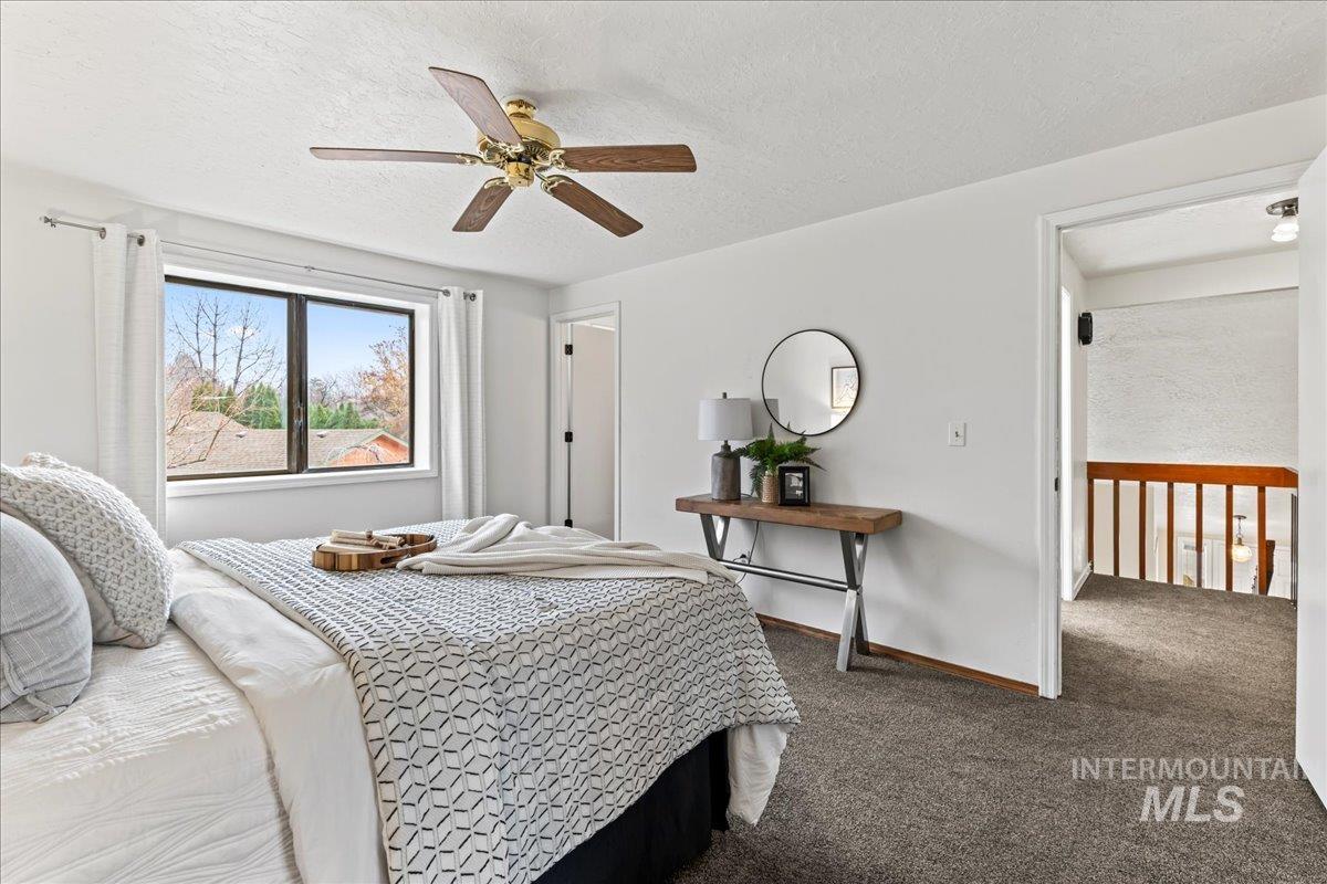 Carpeted bedroom featuring a textured ceiling and ceiling fan