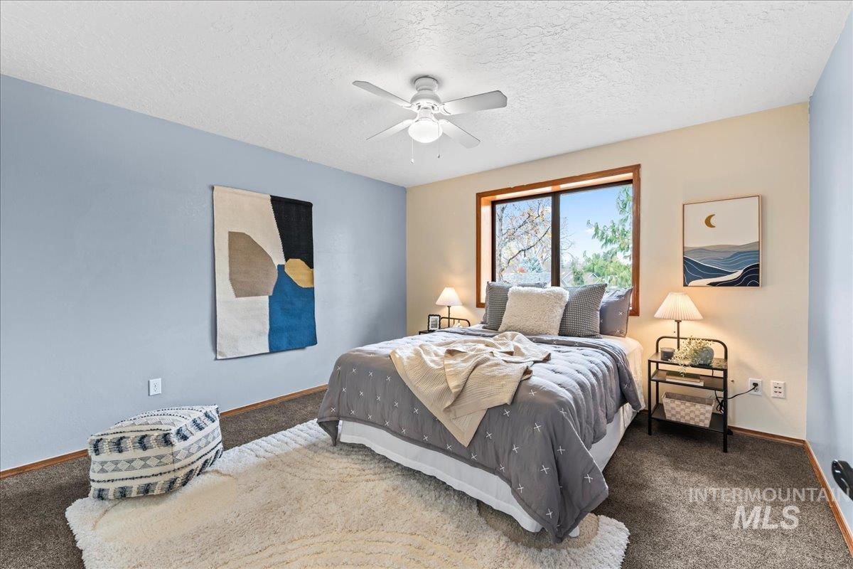 Carpeted bedroom with a textured ceiling and a ceiling fan