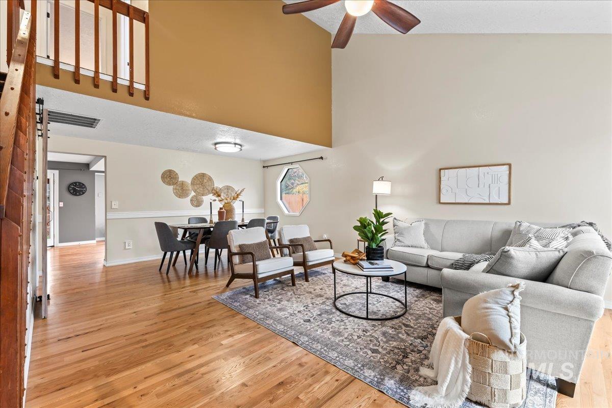 Living room with light wood-style floors, high vaulted ceiling, and ceiling fan