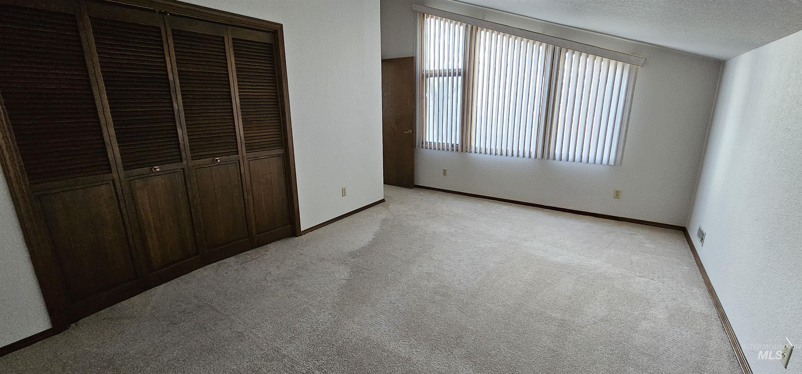 Unfurnished bedroom with light colored carpet, a closet, and a textured ceiling