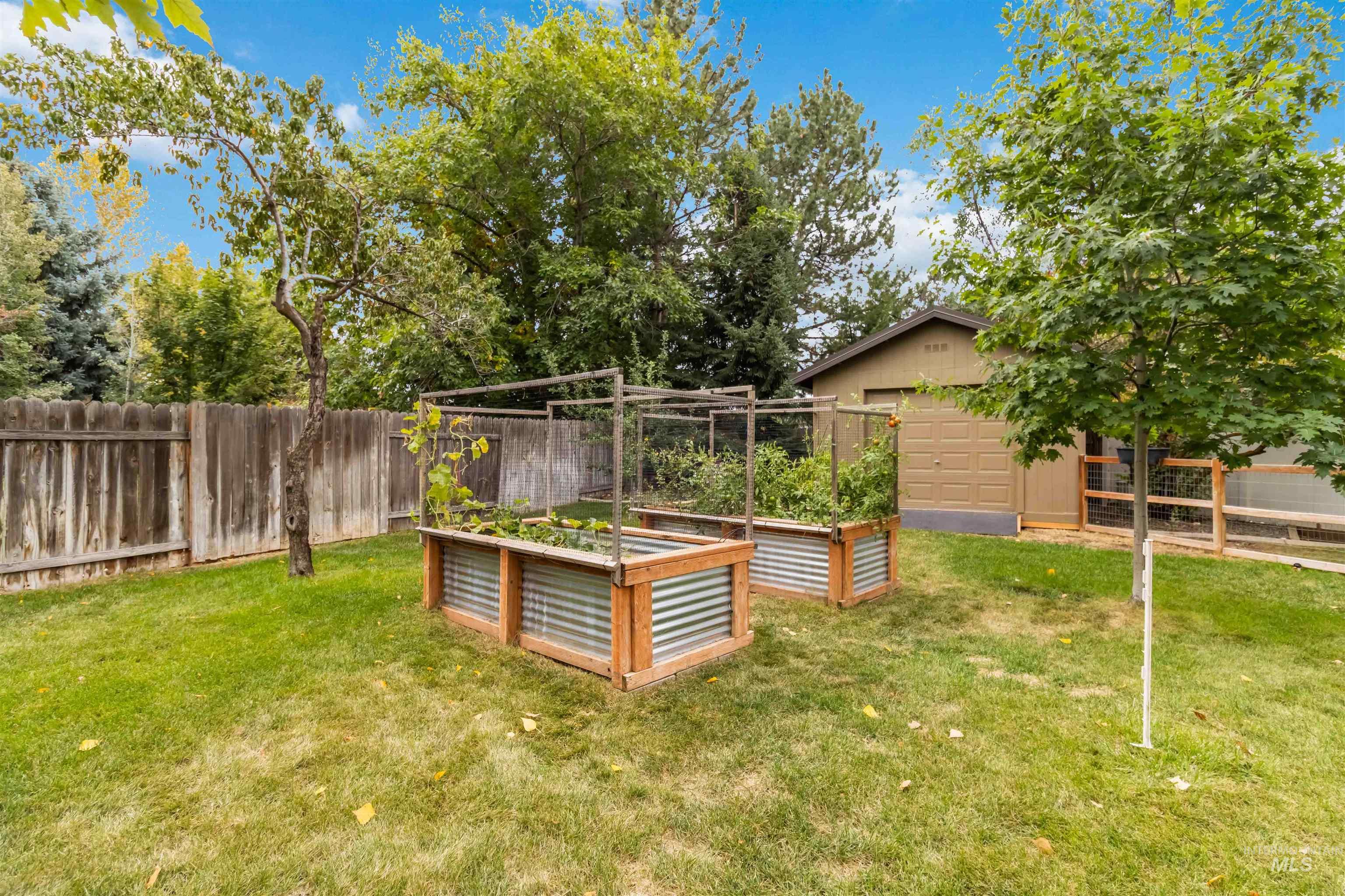 Fenced backyard featuring a vegetable garden and an outbuilding