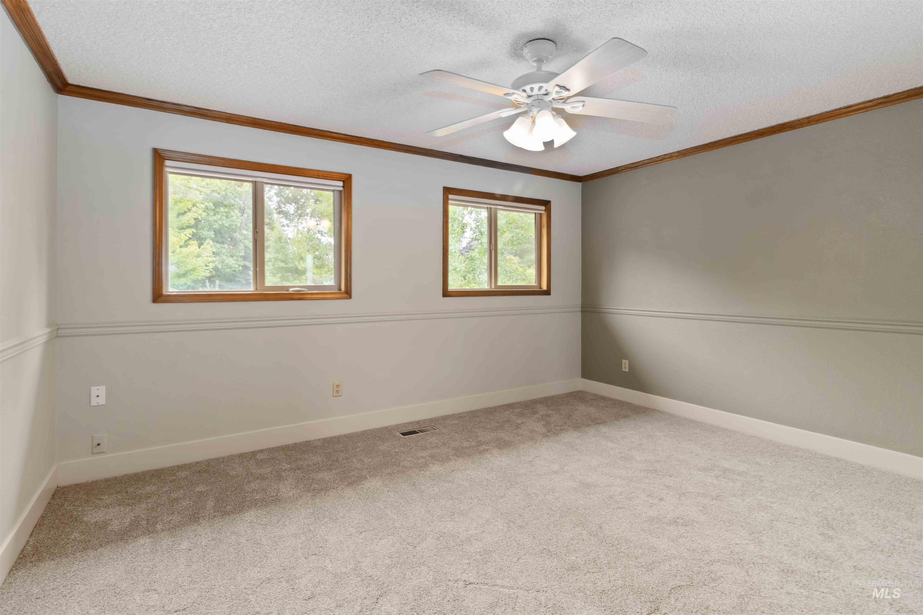 Empty room with crown molding, light carpet, a textured ceiling, and ceiling fan