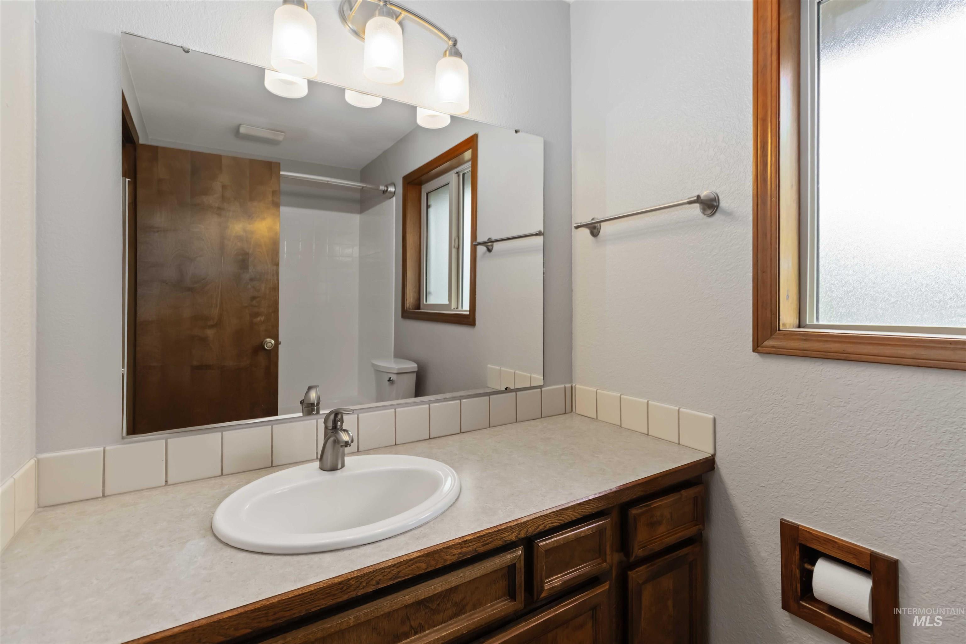 Bathroom with vanity, a textured wall, and a shower
