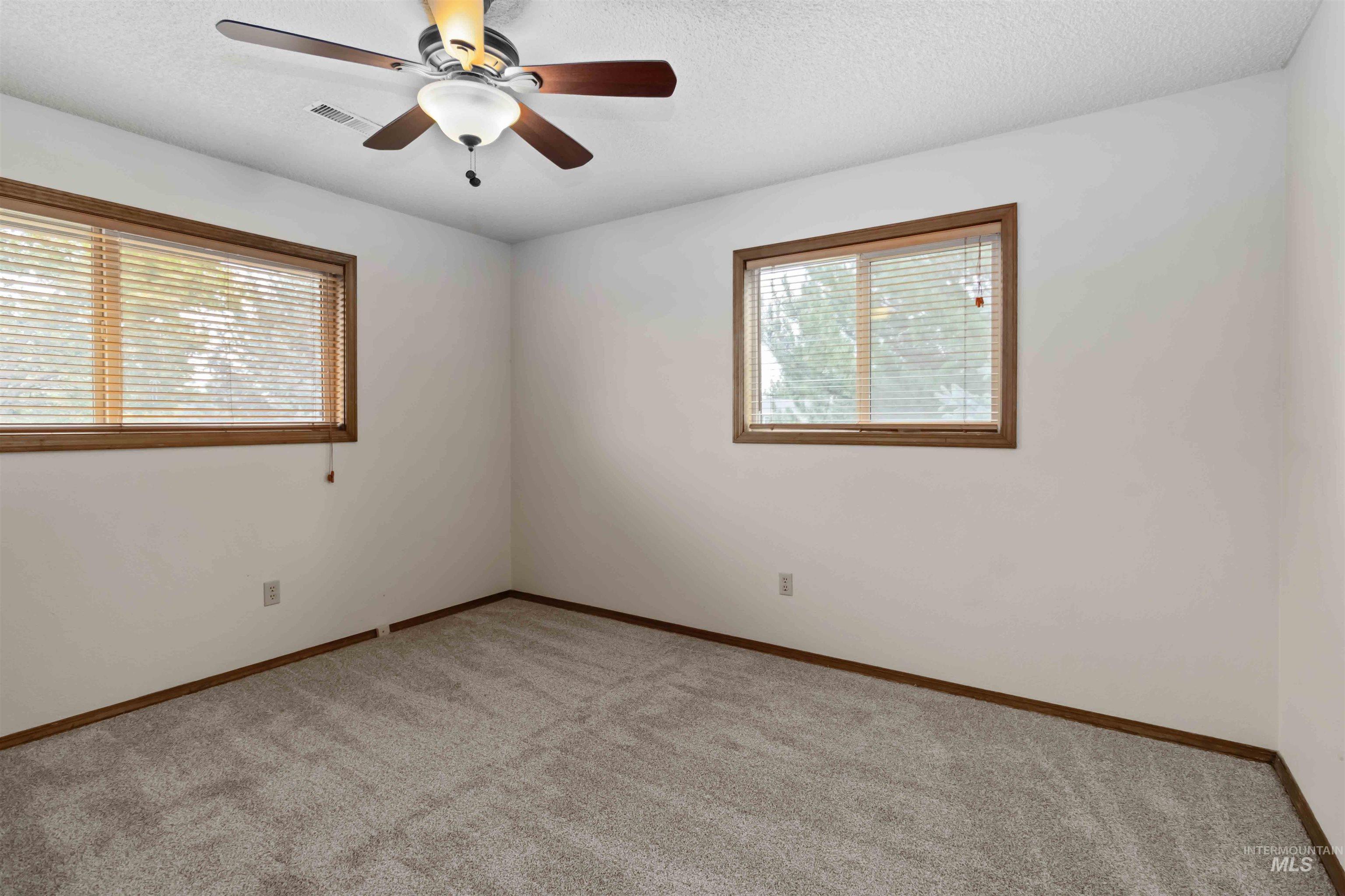 Unfurnished room with a textured ceiling, light carpet, and a ceiling fan