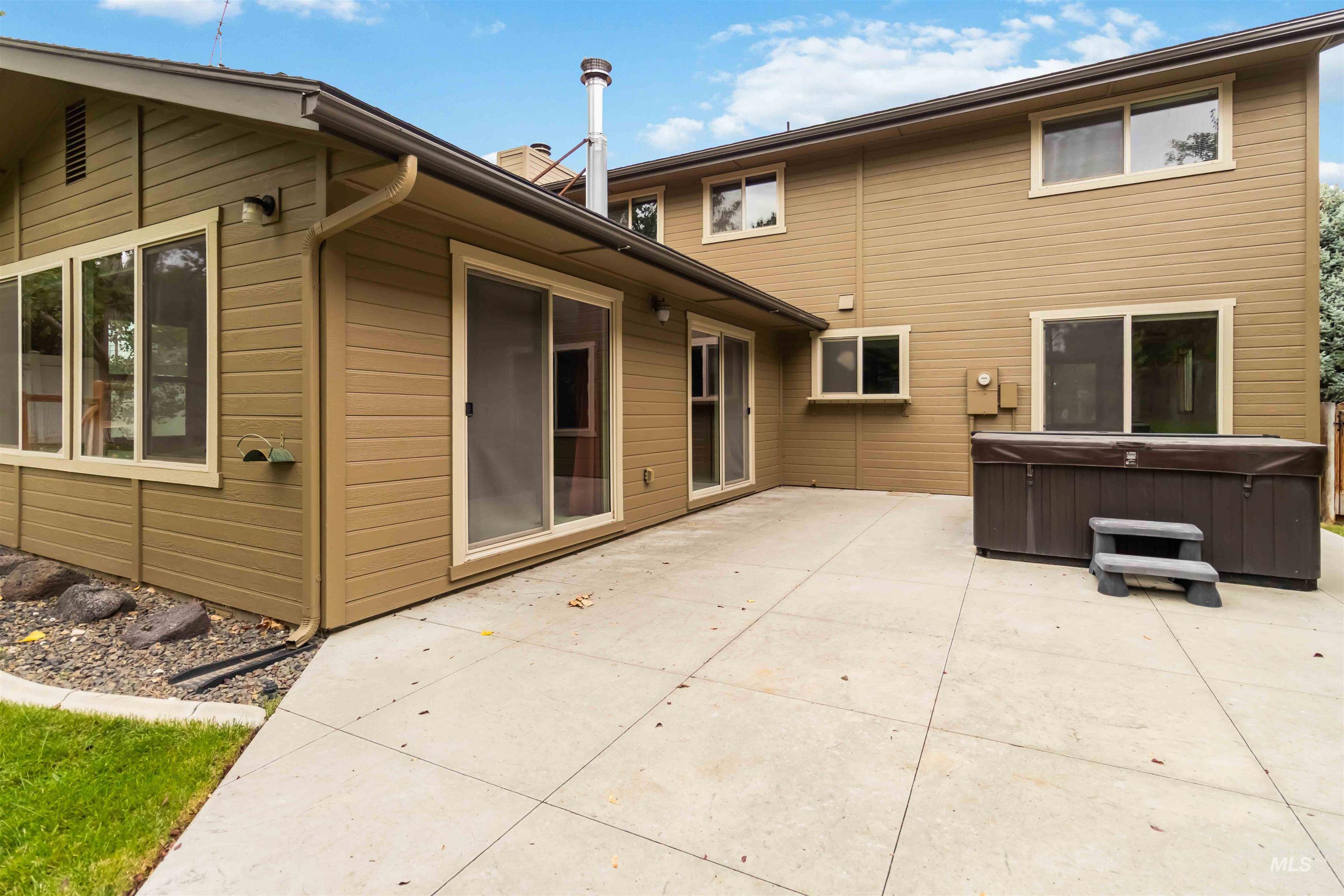 Rear view of house with a hot tub, a patio, and a chimney