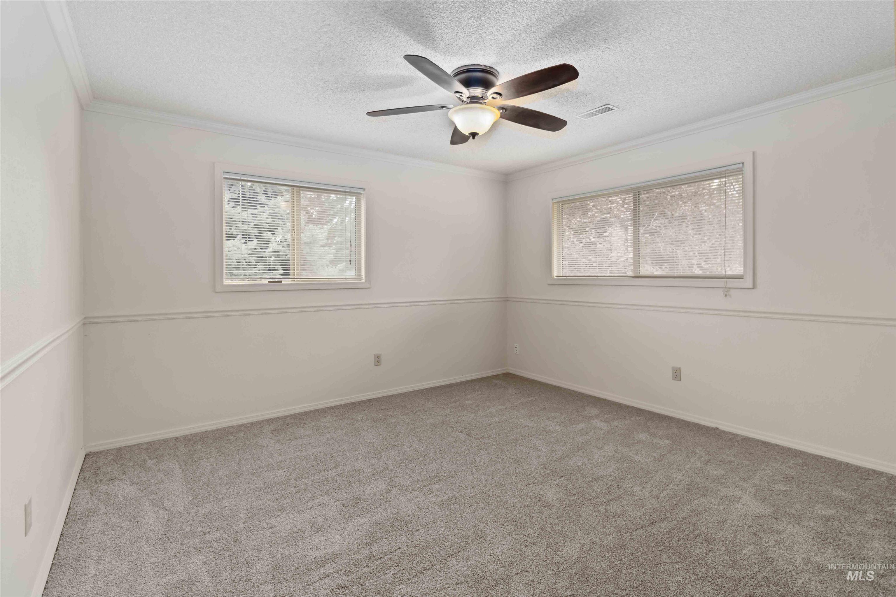 Unfurnished room featuring ornamental molding, light colored carpet, a textured ceiling, and a ceiling fan