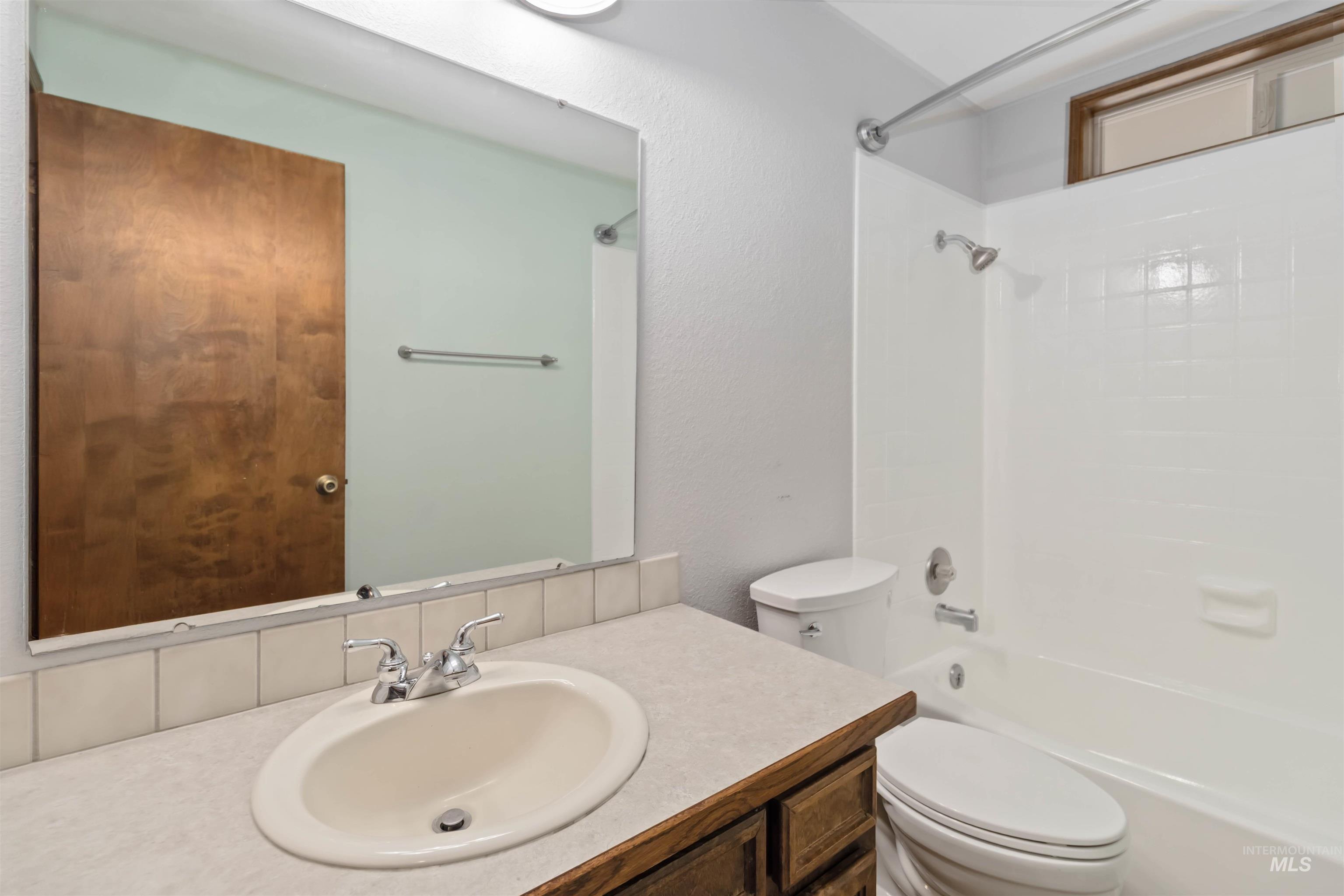 Bathroom with washtub / shower combination, vanity, and a textured wall
