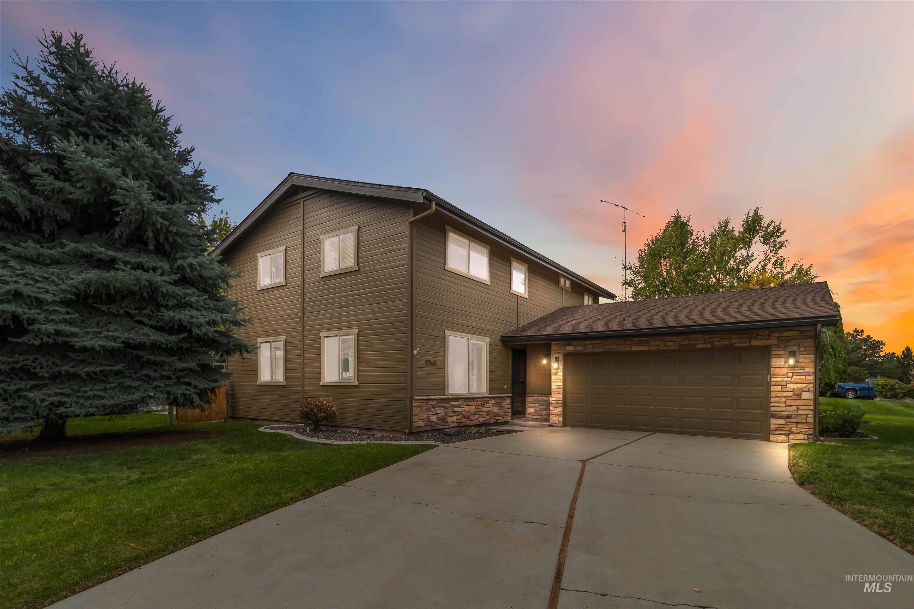 View of front of house with stone siding, a yard, driveway, and an attached garage