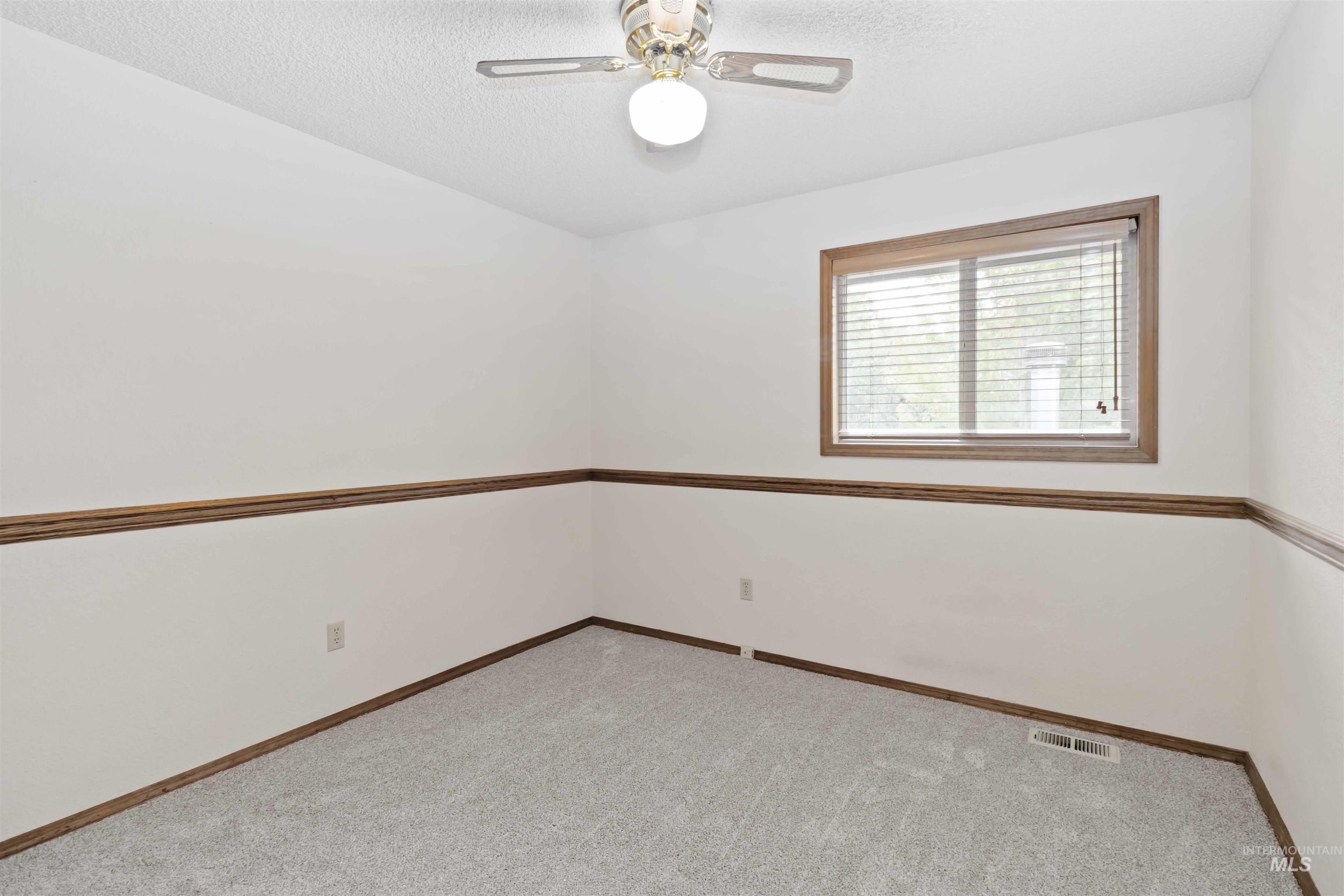 Spare room featuring light colored carpet, a textured ceiling, and a ceiling fan