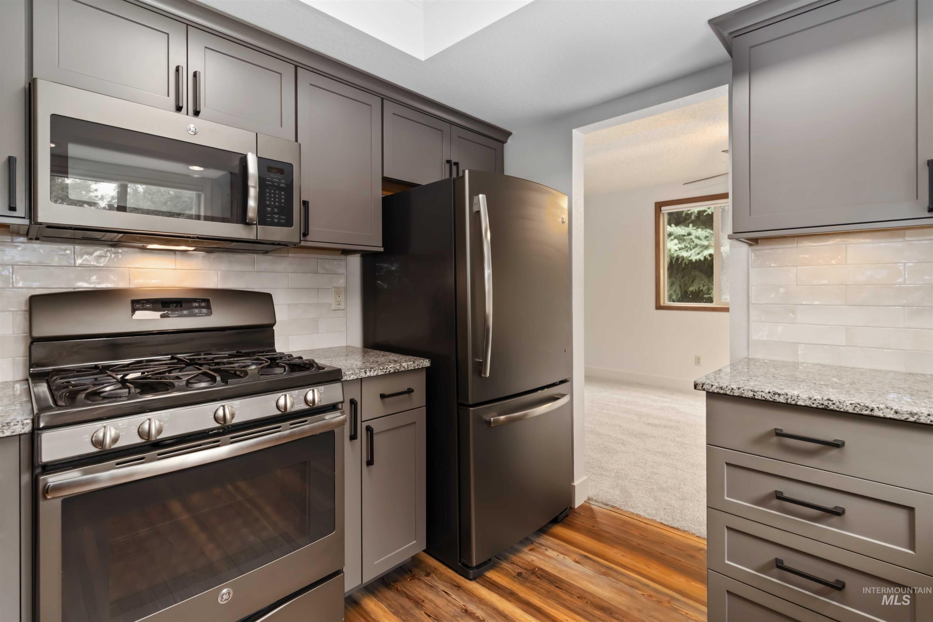 Kitchen with gray cabinetry, appliances with stainless steel finishes, and decorative backsplash