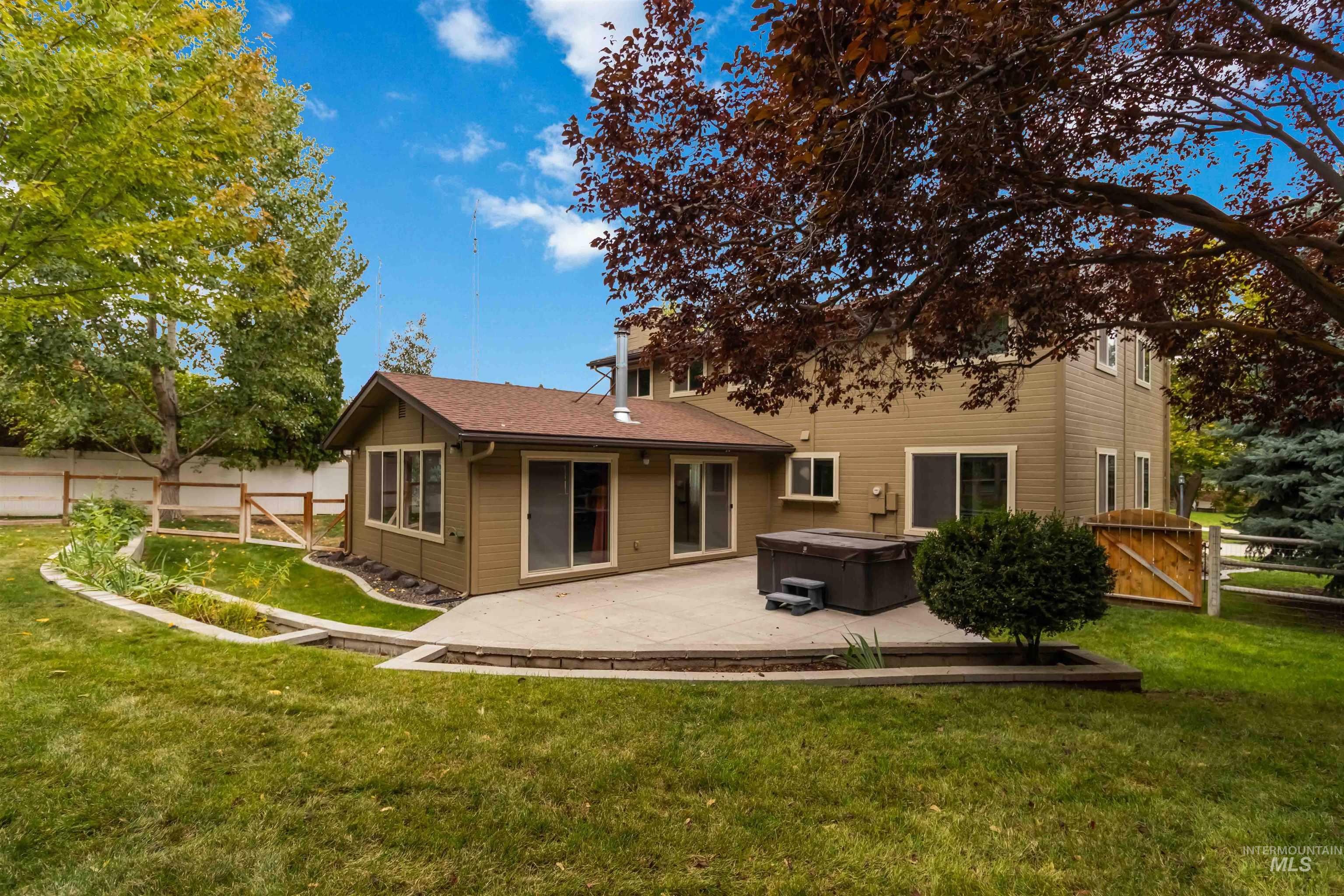 Rear view of house with a hot tub, a gate, a patio area, and a sunroom
