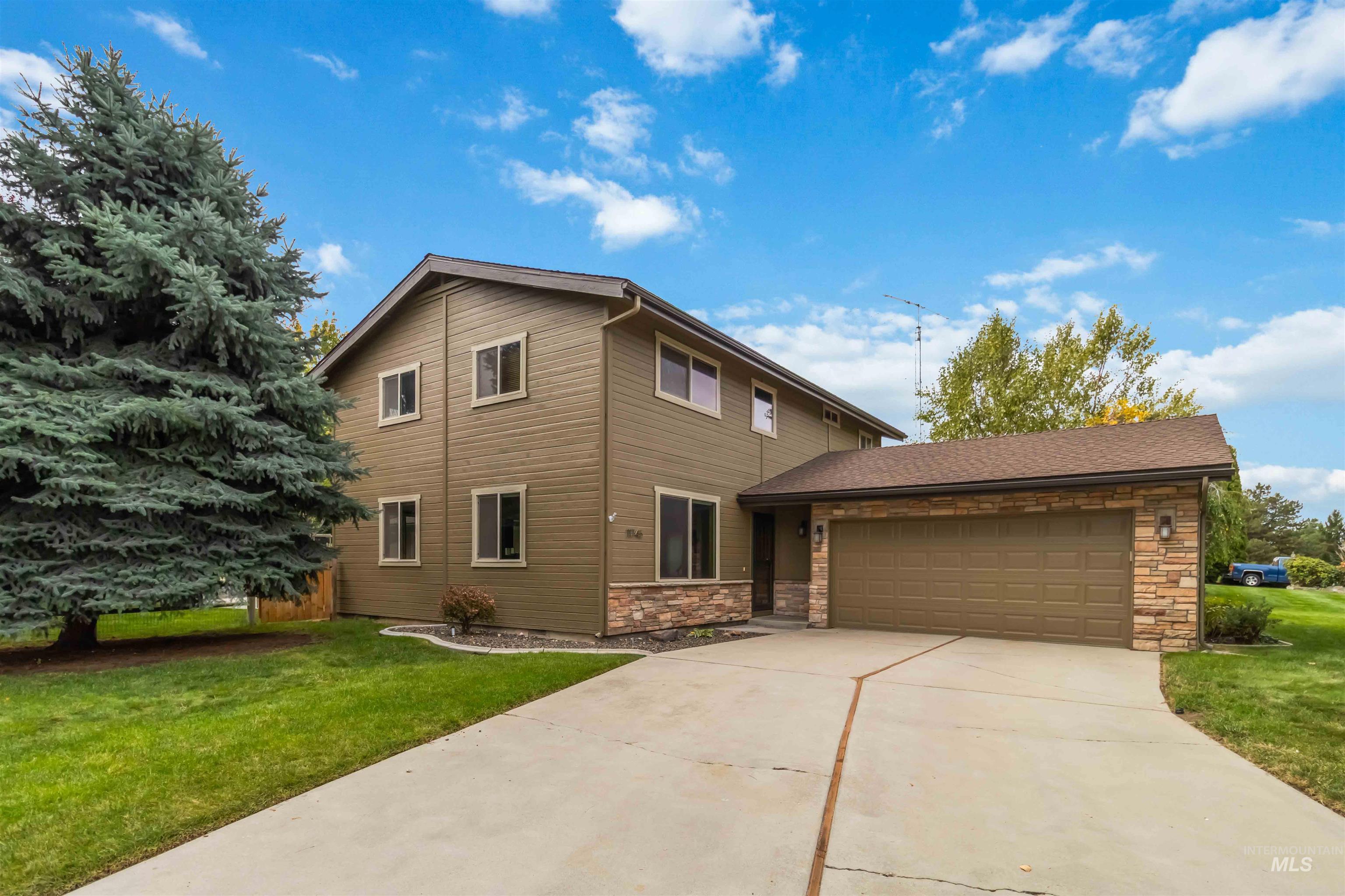 Traditional-style house featuring a front lawn, stone siding, driveway, and a garage