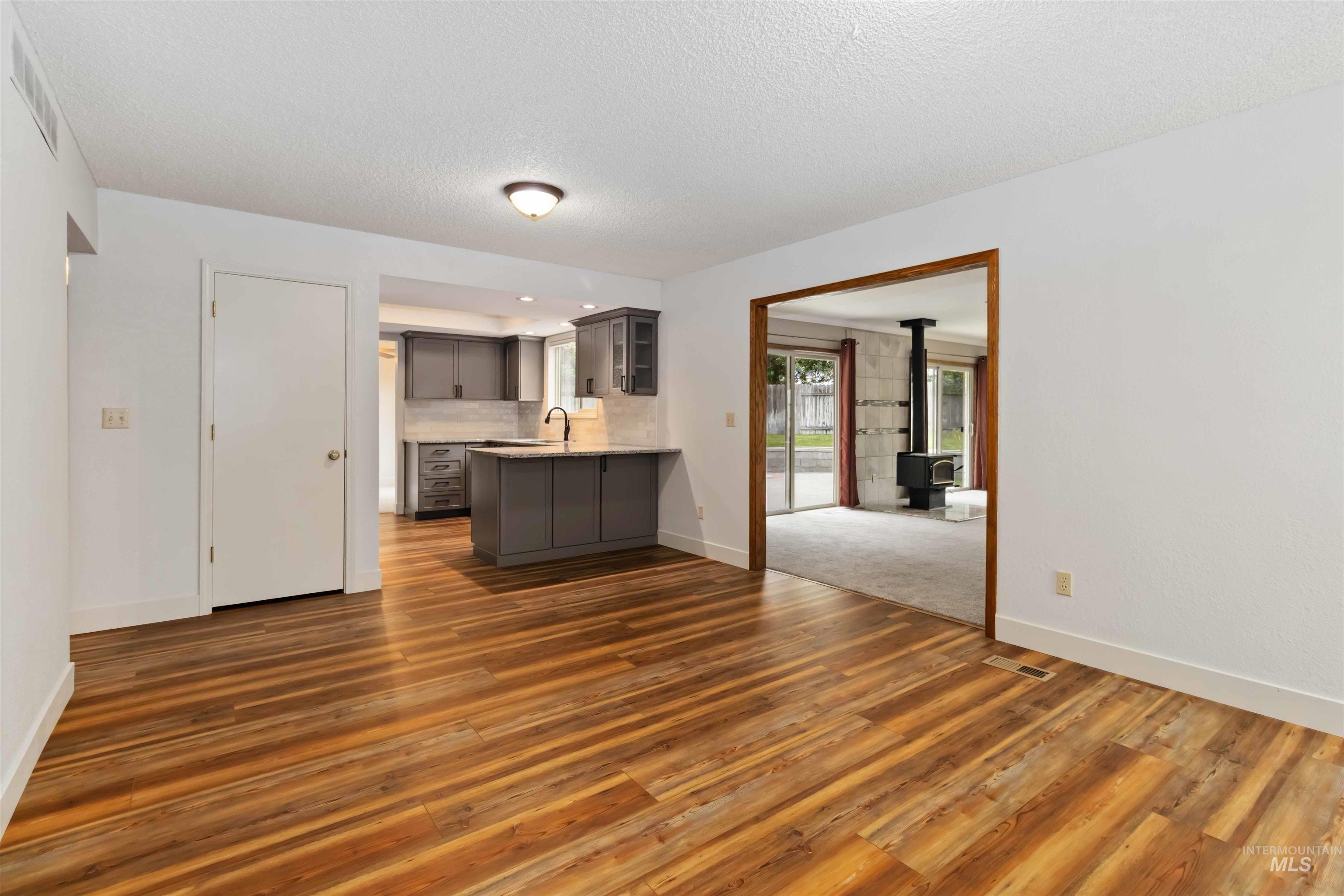 Kitchen with a wood stove, glass insert cabinets, dark wood-style floors, gray cabinets, and a textured ceiling