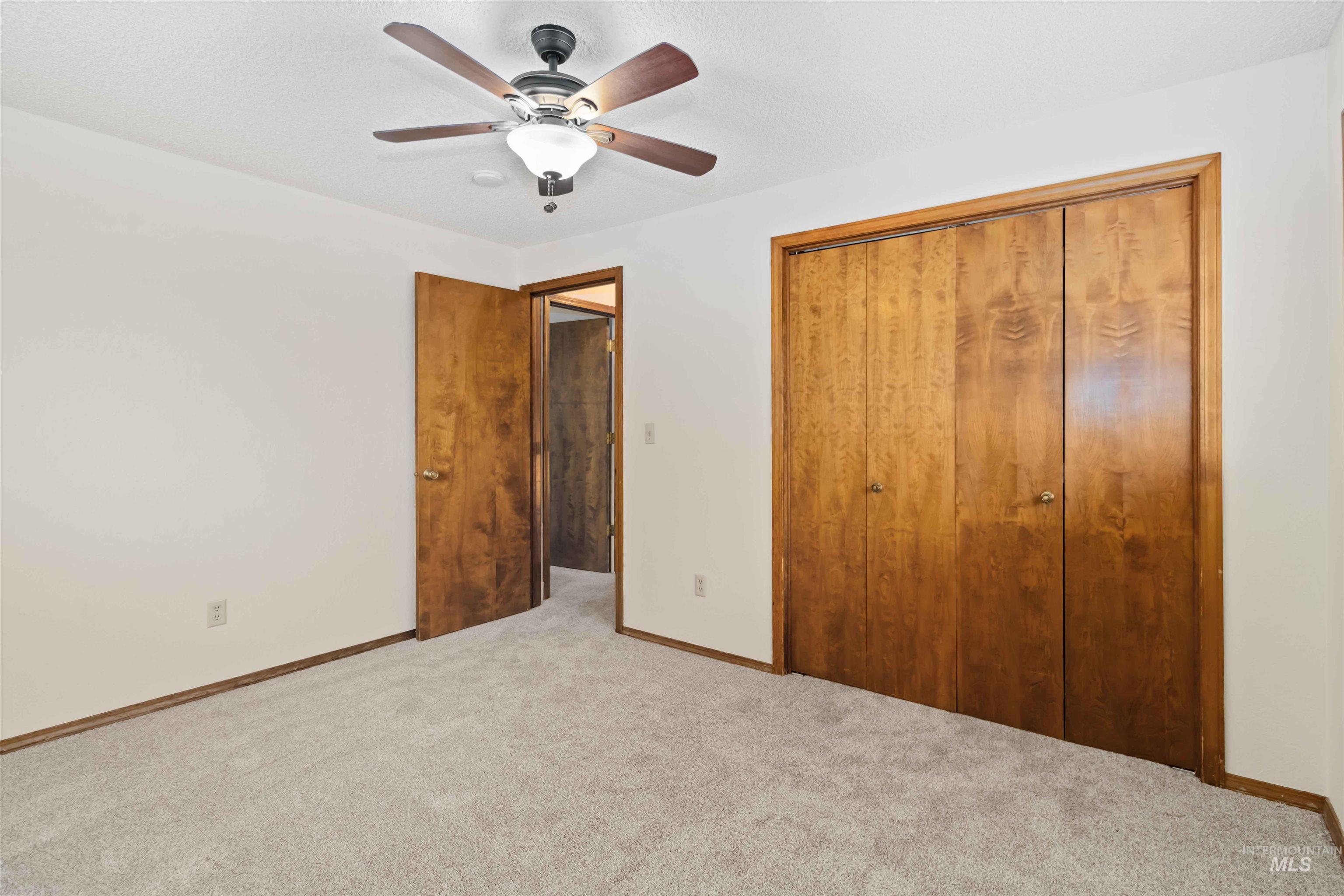 Unfurnished bedroom featuring a closet, carpet floors, a ceiling fan, and a textured ceiling