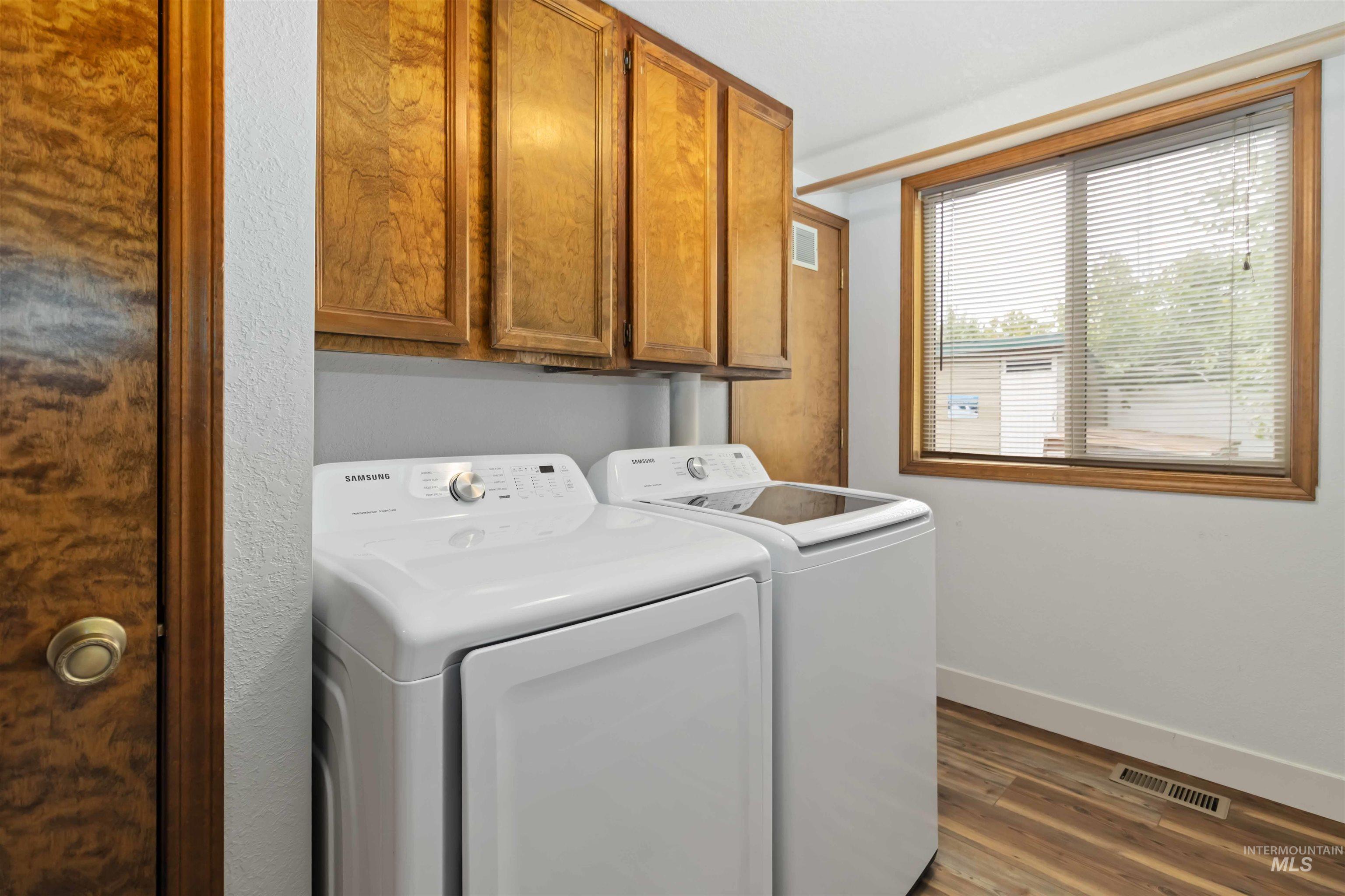 Washroom featuring cabinet space, dark wood-type flooring, and washing machine and dryer