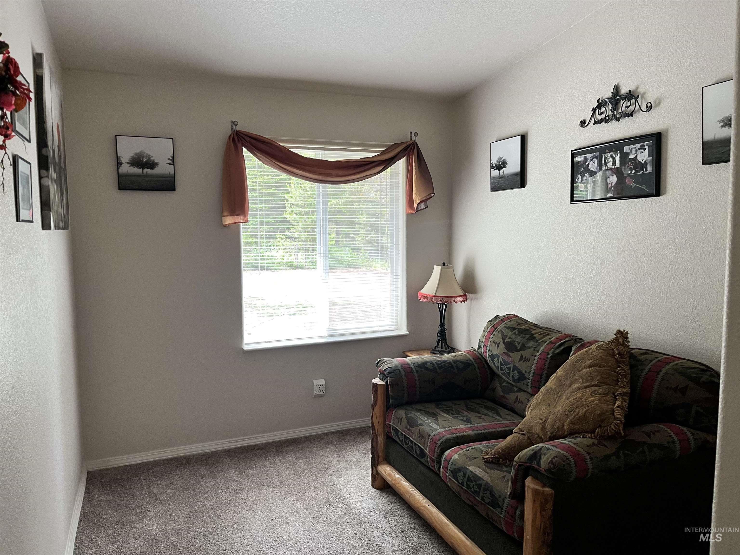 Sitting room featuring carpet and a textured wall