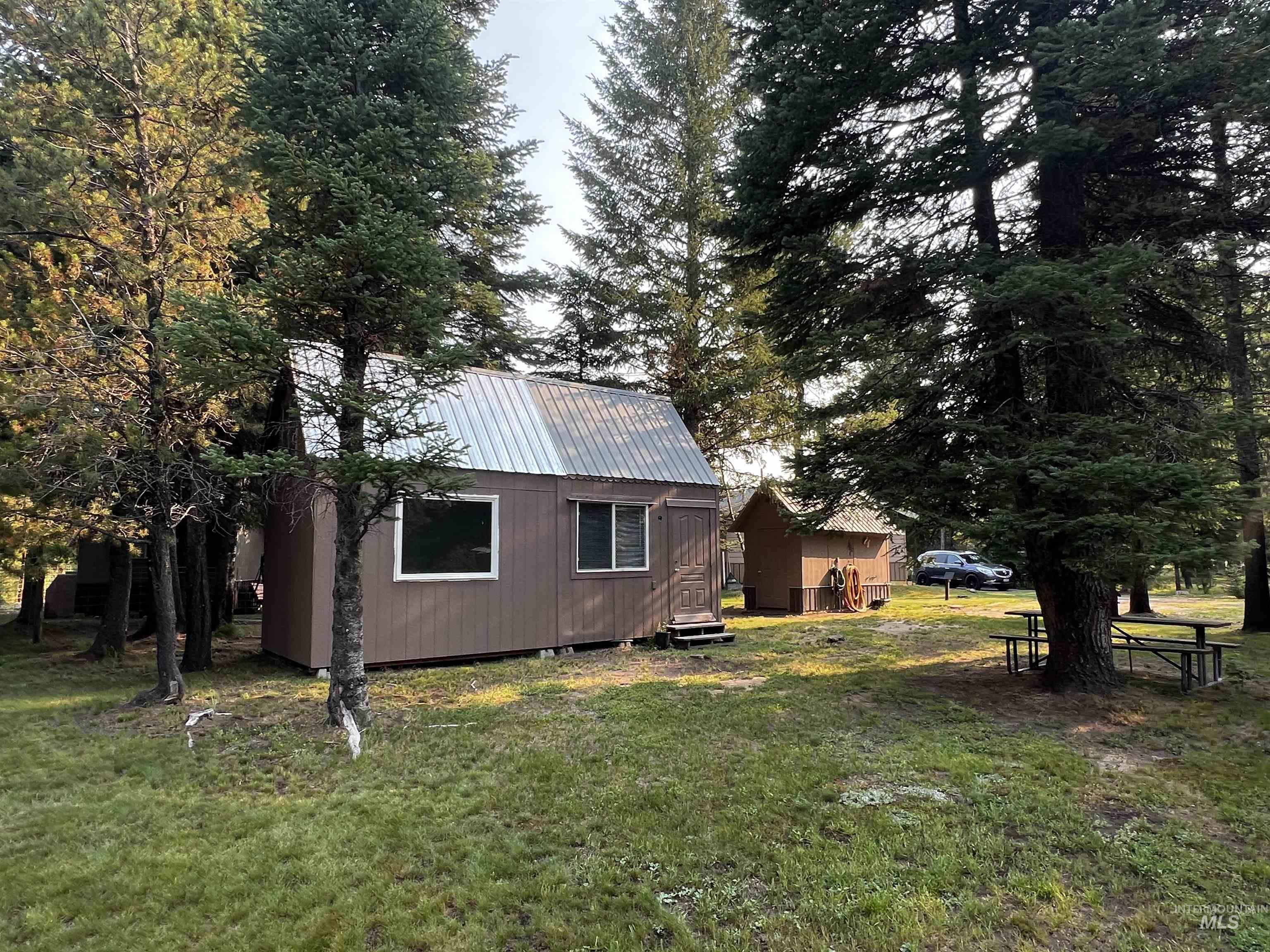 View of side of home with a yard, a metal roof, and an outdoor structure