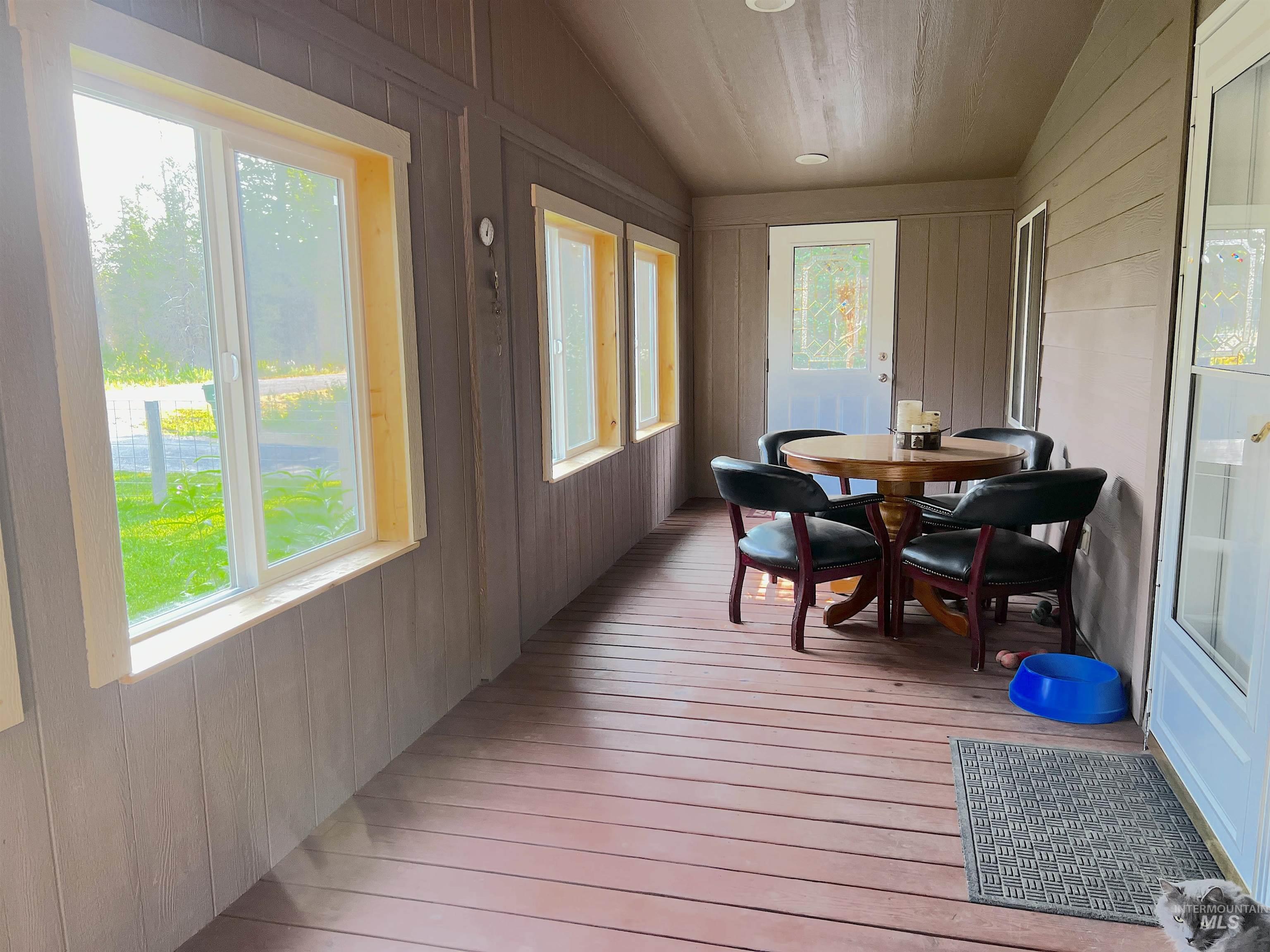 Sunroom / solarium with lofted ceiling, hardwood / wood-style flooring, and wooden walls
