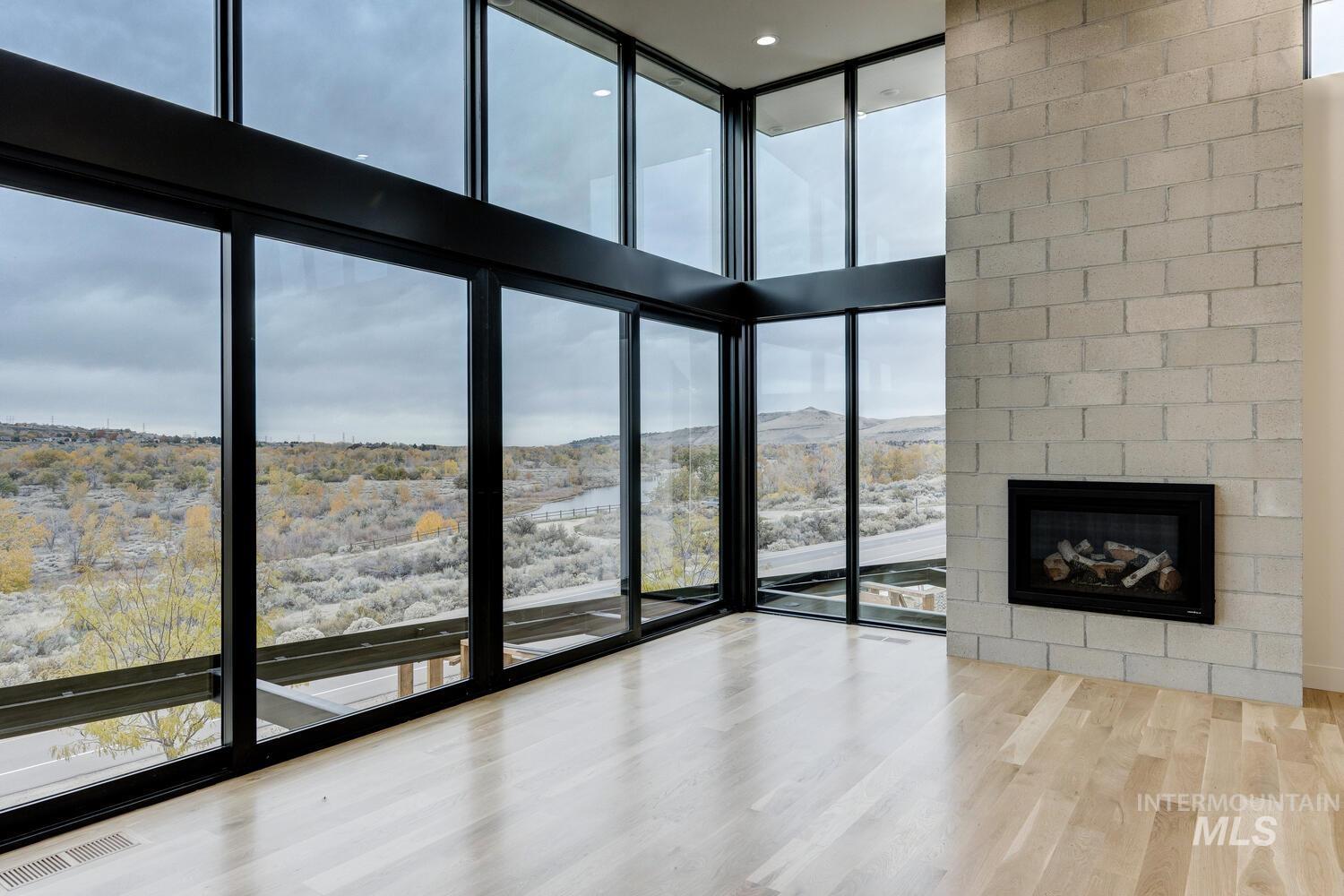 Unfurnished living room with light wood-style flooring, floor to ceiling windows, a large fireplace, a high ceiling, and a mountain view
