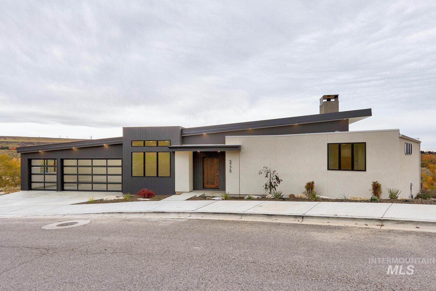 Modern home with a garage, driveway, and a chimney