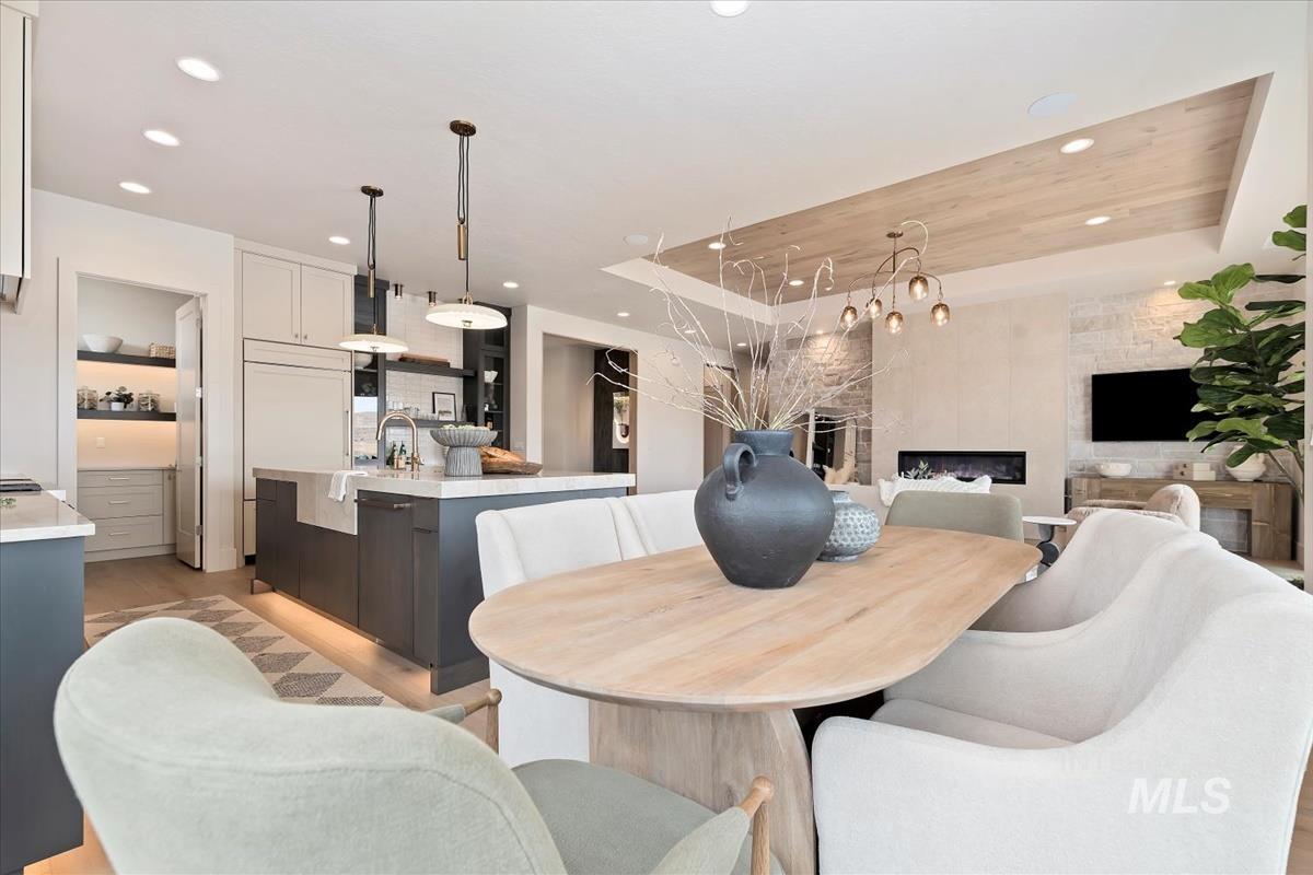 Dining room with a raised ceiling, light wood-type flooring, and recessed lighting