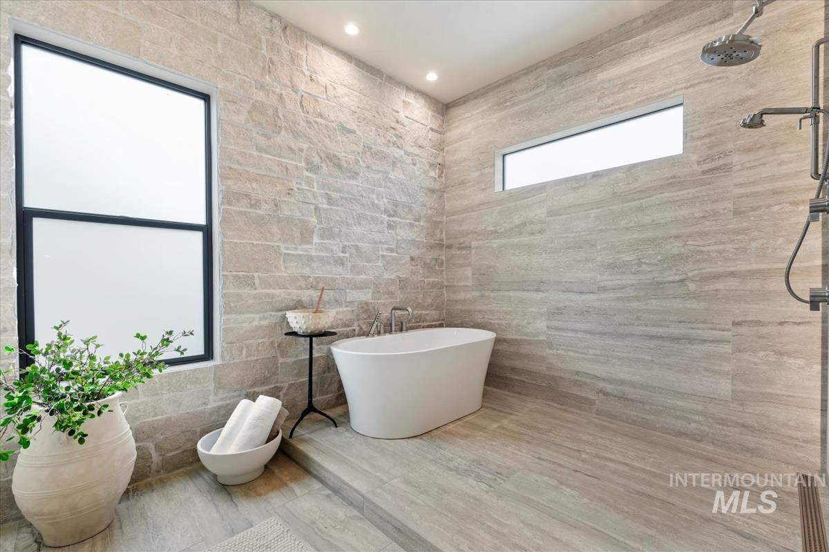 Bathroom with tile walls, a freestanding tub, a tile shower, and recessed lighting