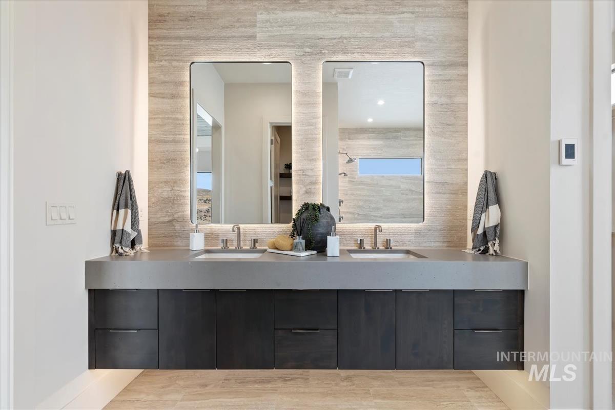 Bathroom with double vanity, a tile shower, wood finished floors, and backsplash