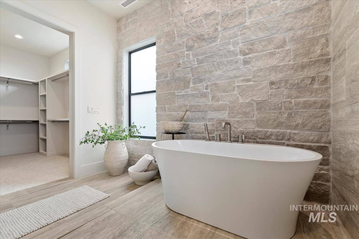 Bathroom with a freestanding bath, a walk in closet, wood finished floors, and recessed lighting