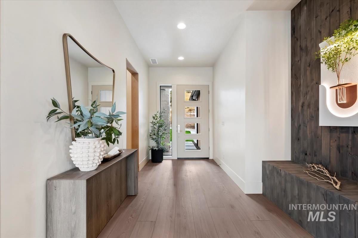 Hallway with light wood finished floors, recessed lighting, and wood walls