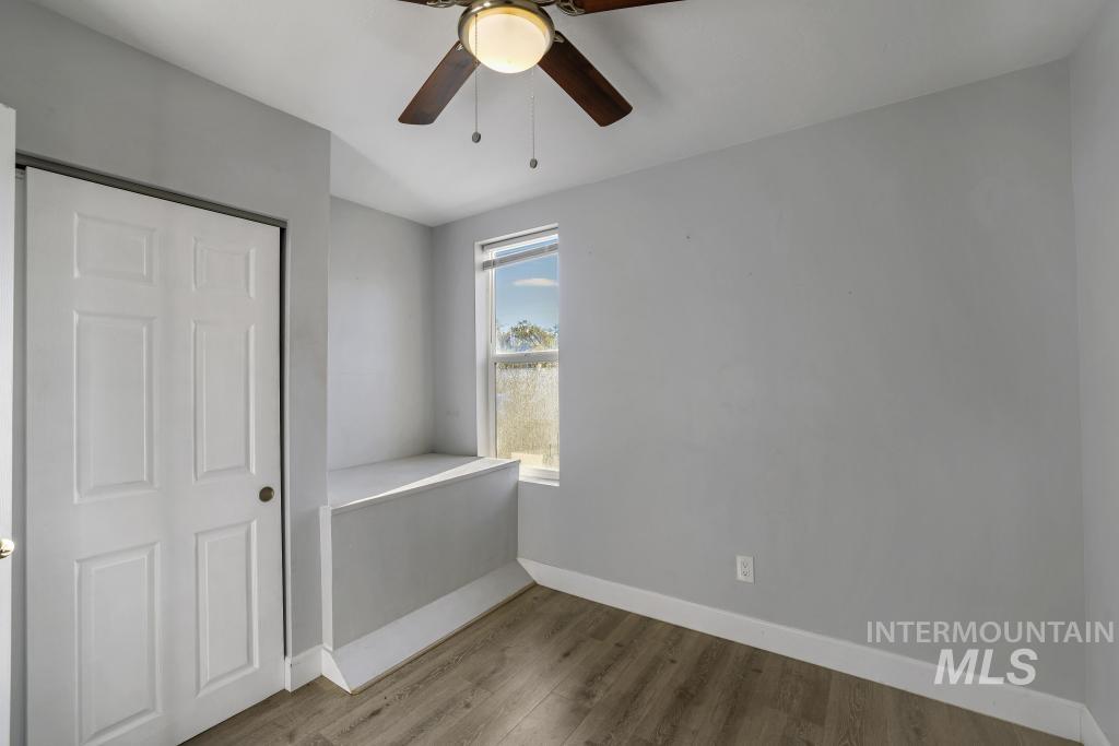 Unfurnished bedroom featuring wood finished floors, a closet, and a ceiling fan