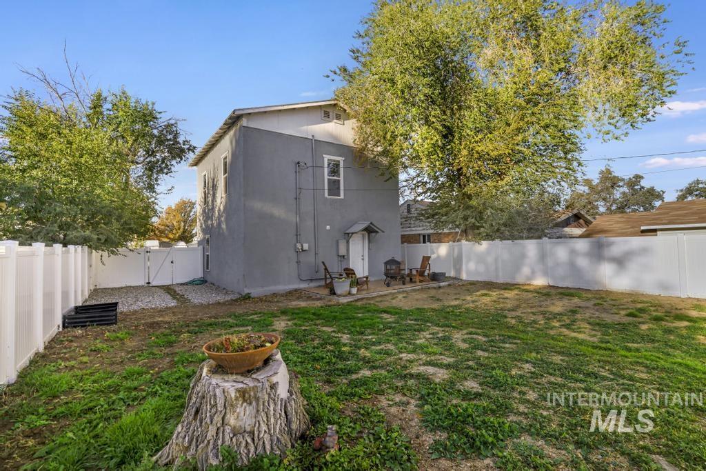 Back of house with a fenced backyard, a patio, stucco siding, and a gate
