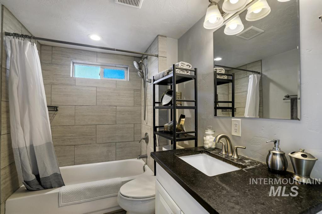 Full bathroom with shower / tub combo with curtain and vanity