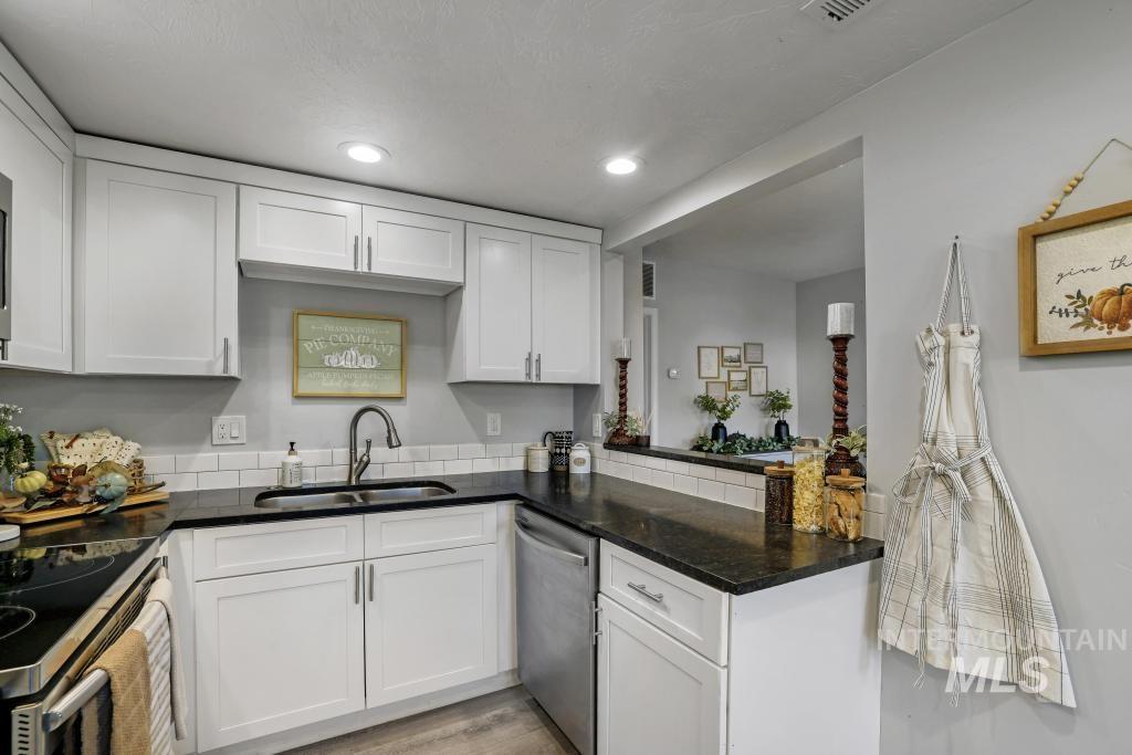 Kitchen with white cabinets, dishwasher, recessed lighting, light wood-style floors, and dark stone counters