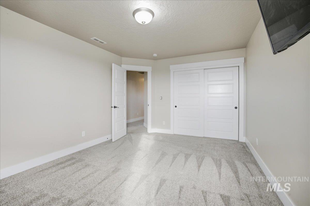 Unfurnished bedroom with a textured ceiling, carpet floors, and a closet
