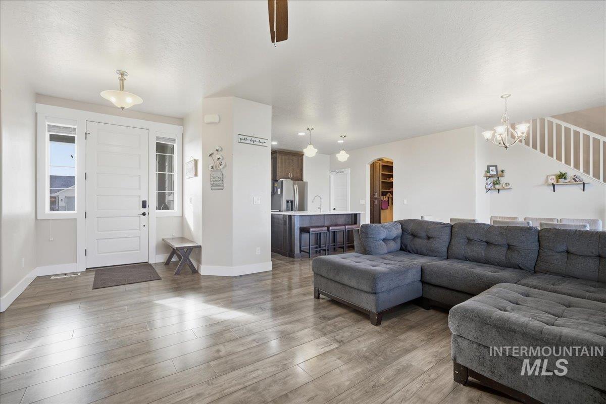 Living area with dark wood-type flooring, arched walkways, a chandelier, a textured ceiling, and stairs