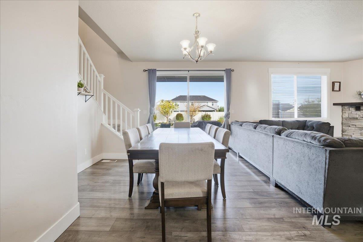Dining room with light wood finished floors, stairs, and a chandelier