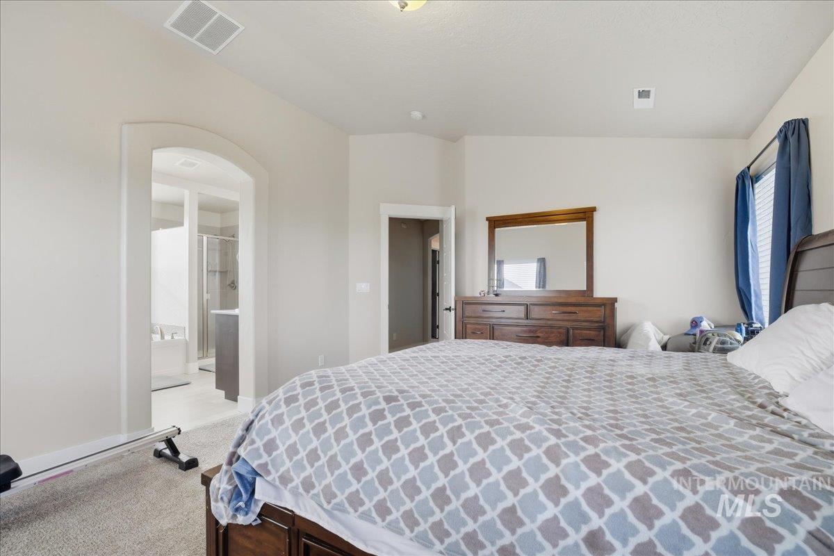 Bedroom featuring carpet, arched walkways, and vaulted ceiling