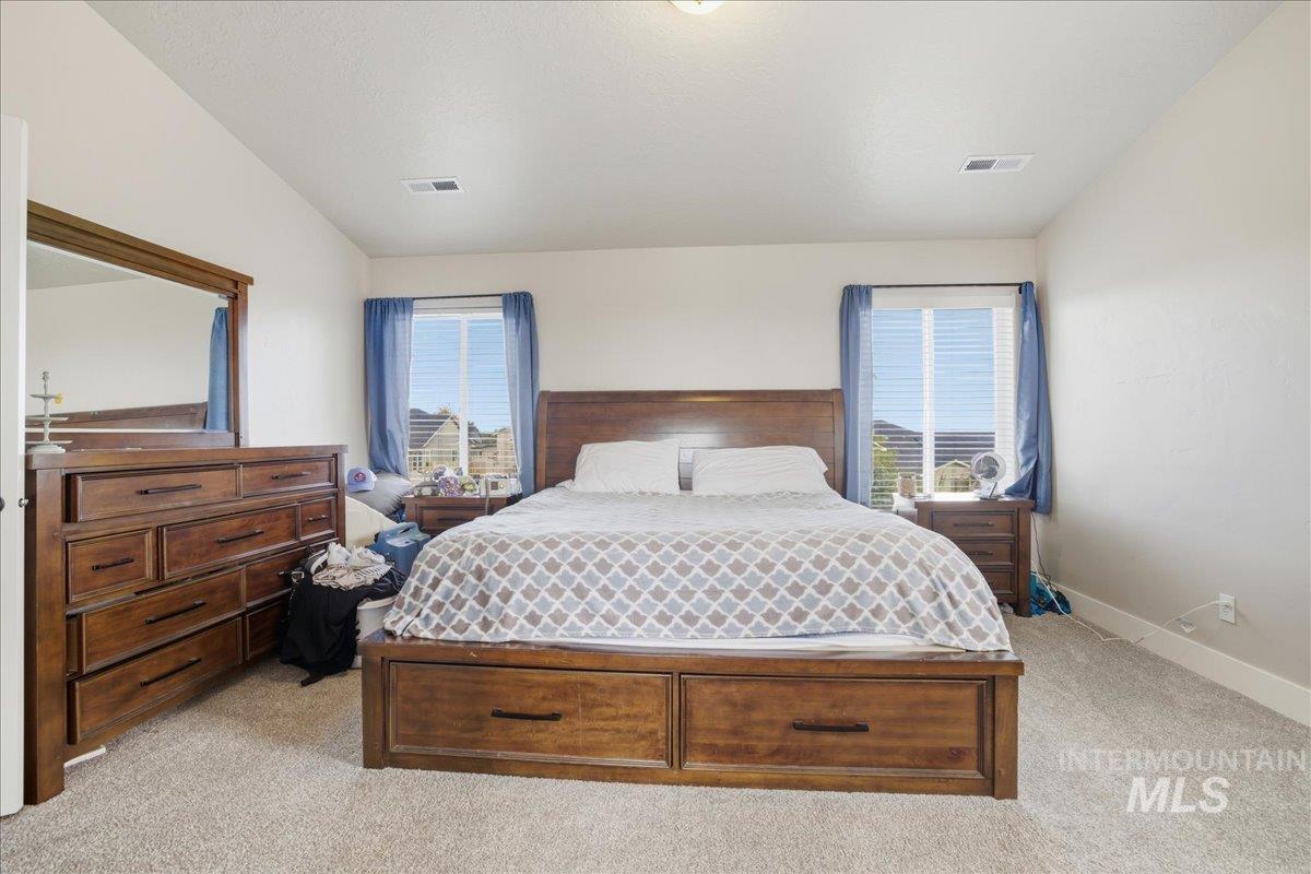 Bedroom with light carpet and lofted ceiling