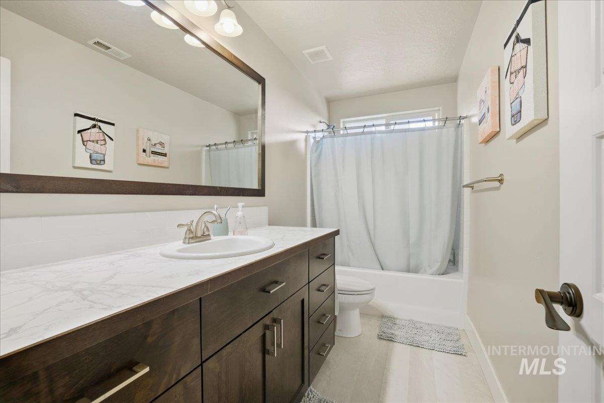 Full bathroom with shower / tub combo with curtain and vanity
