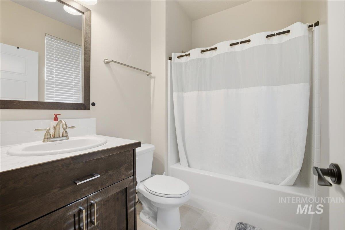 Bathroom with shower / bath combo, vanity, and tile patterned floors
