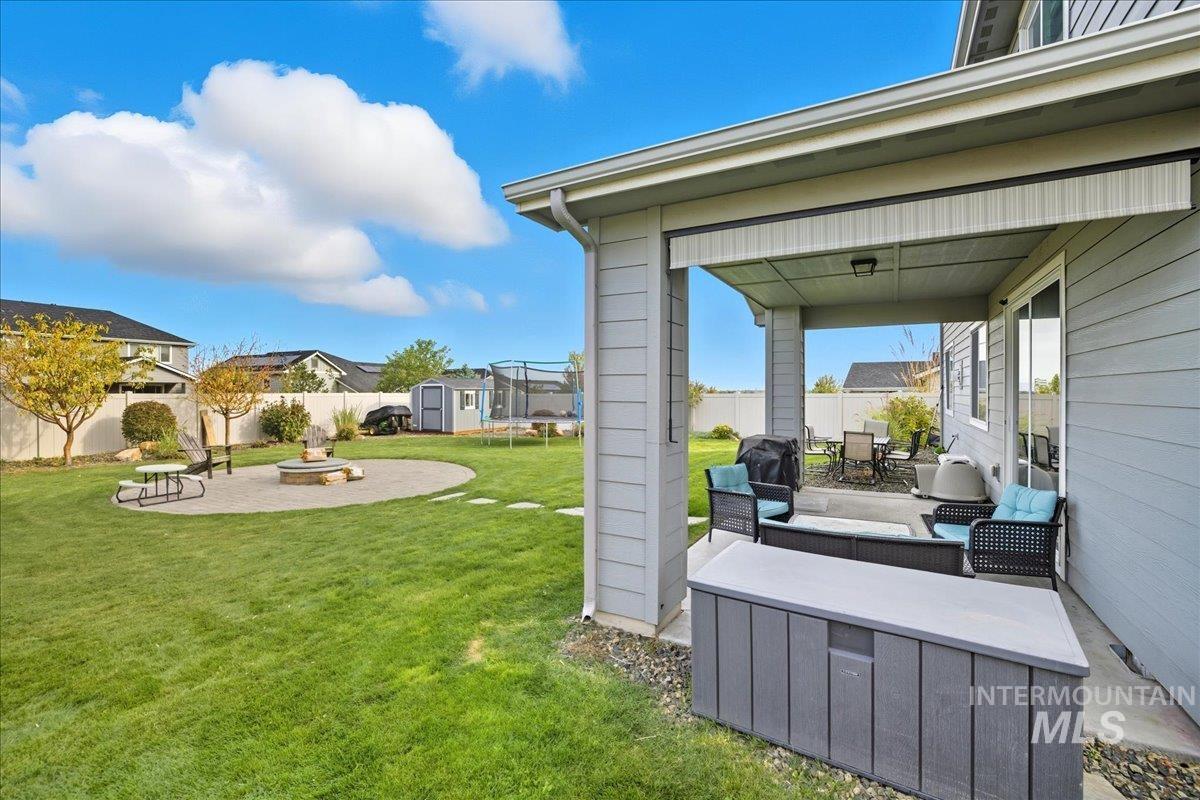 Fenced backyard featuring a patio, an outdoor living space with a fire pit, and a storage unit