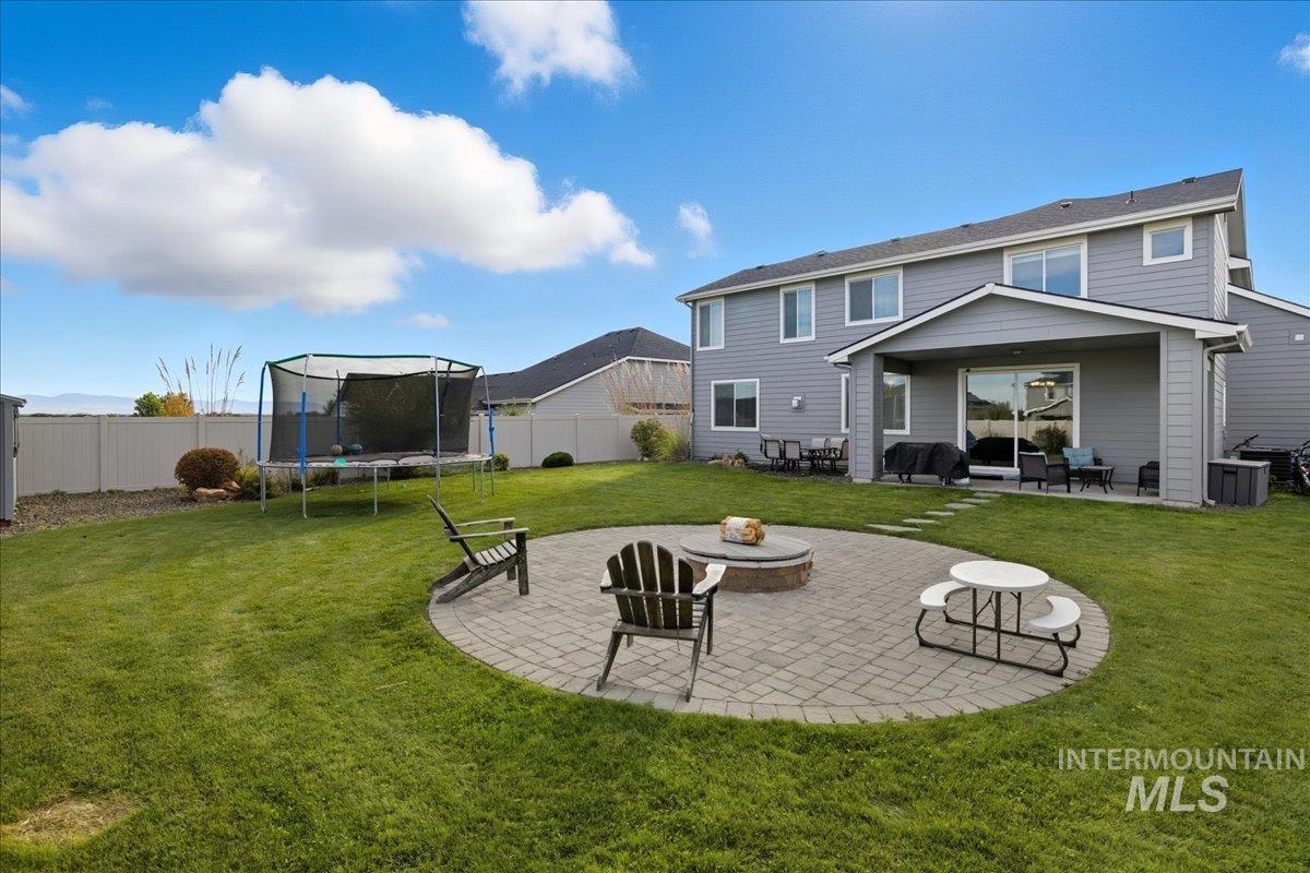 Rear view of house with a patio, a fire pit, a trampoline, and a fenced backyard