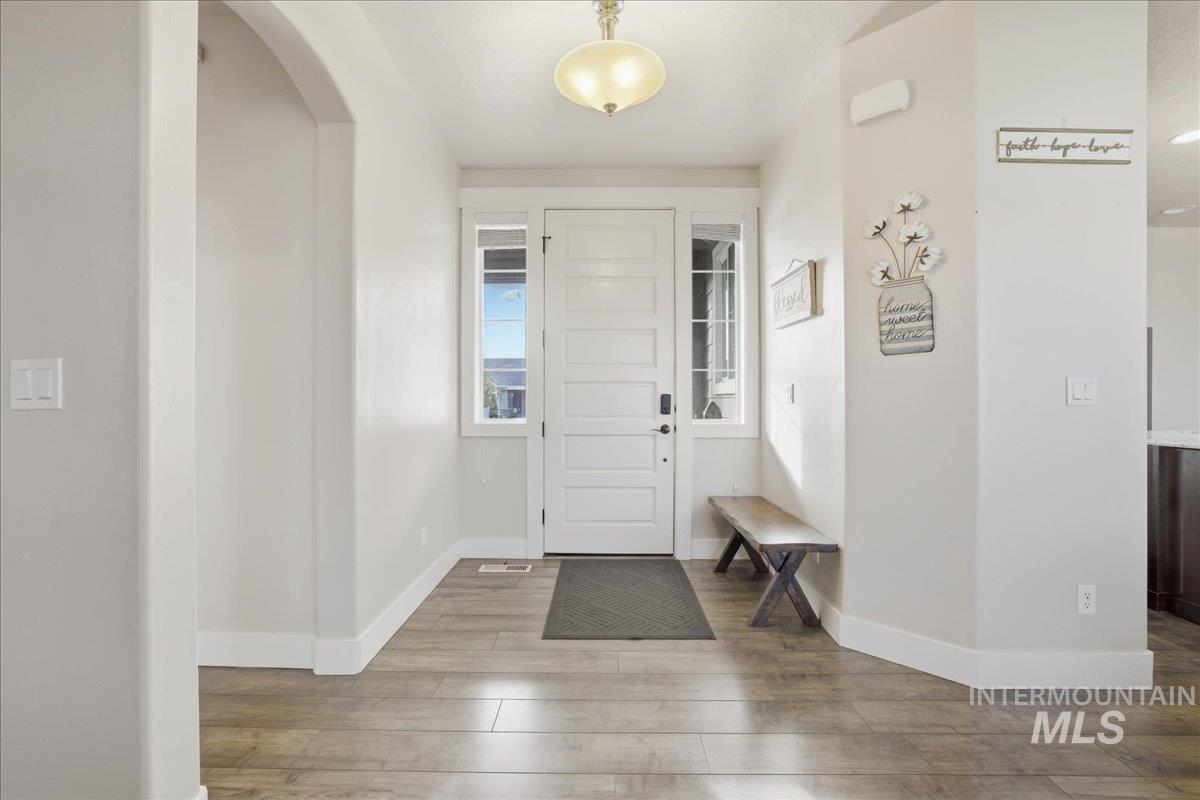 Entryway with light wood finished floors and arched walkways