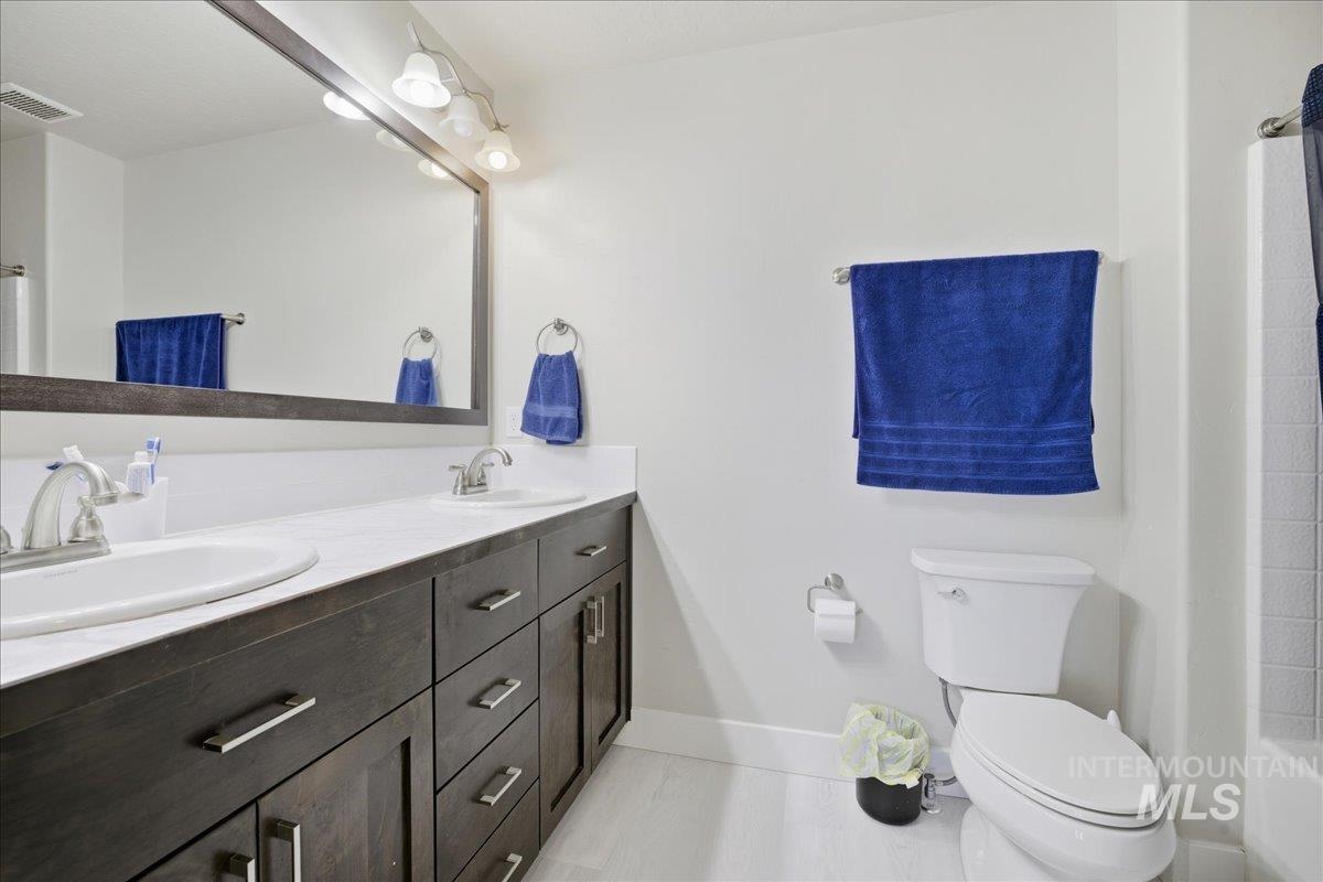 Full bath featuring double vanity and toilet