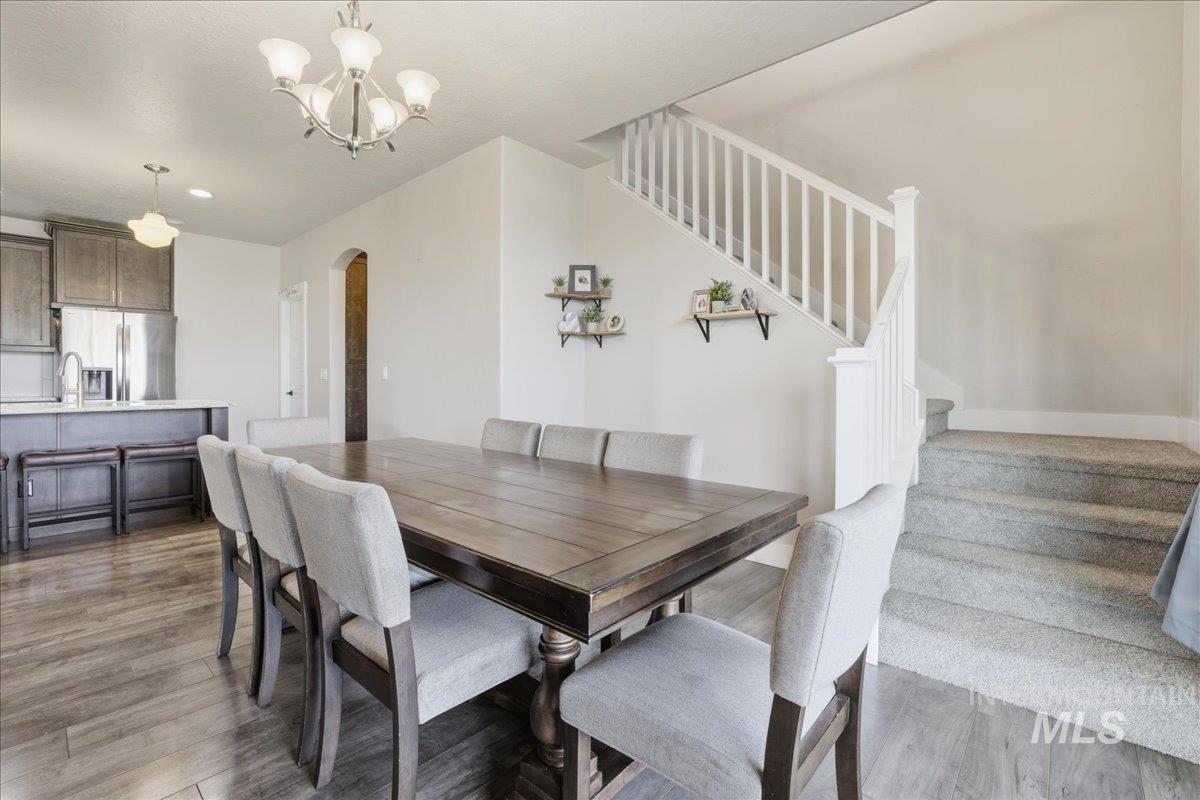 Dining room with stairway, light wood finished floors, a chandelier, and arched walkways