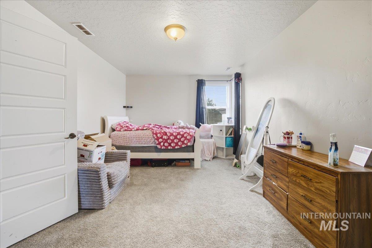Bedroom featuring light carpet and a textured ceiling