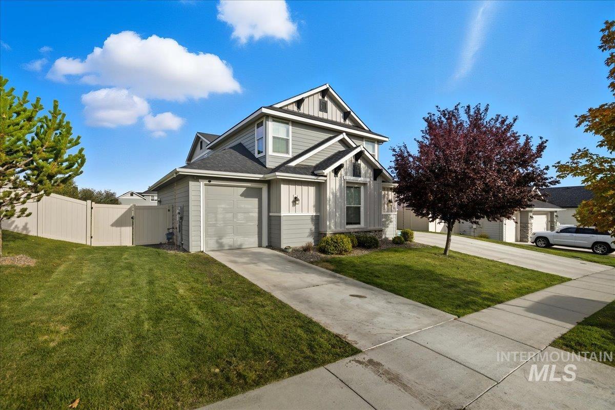 View of front of home with board and batten siding, a gate, a garage, and driveway