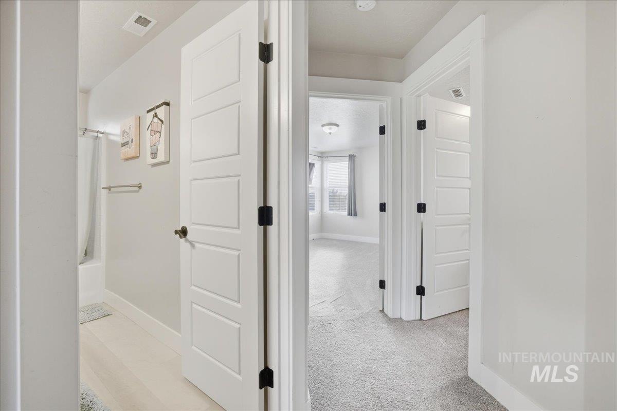 Corridor featuring baseboards and light colored carpet