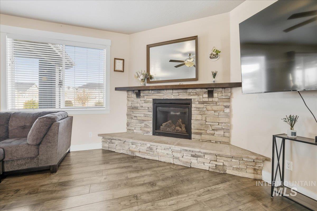 Living room with wood finished floors, a ceiling fan, and a fireplace